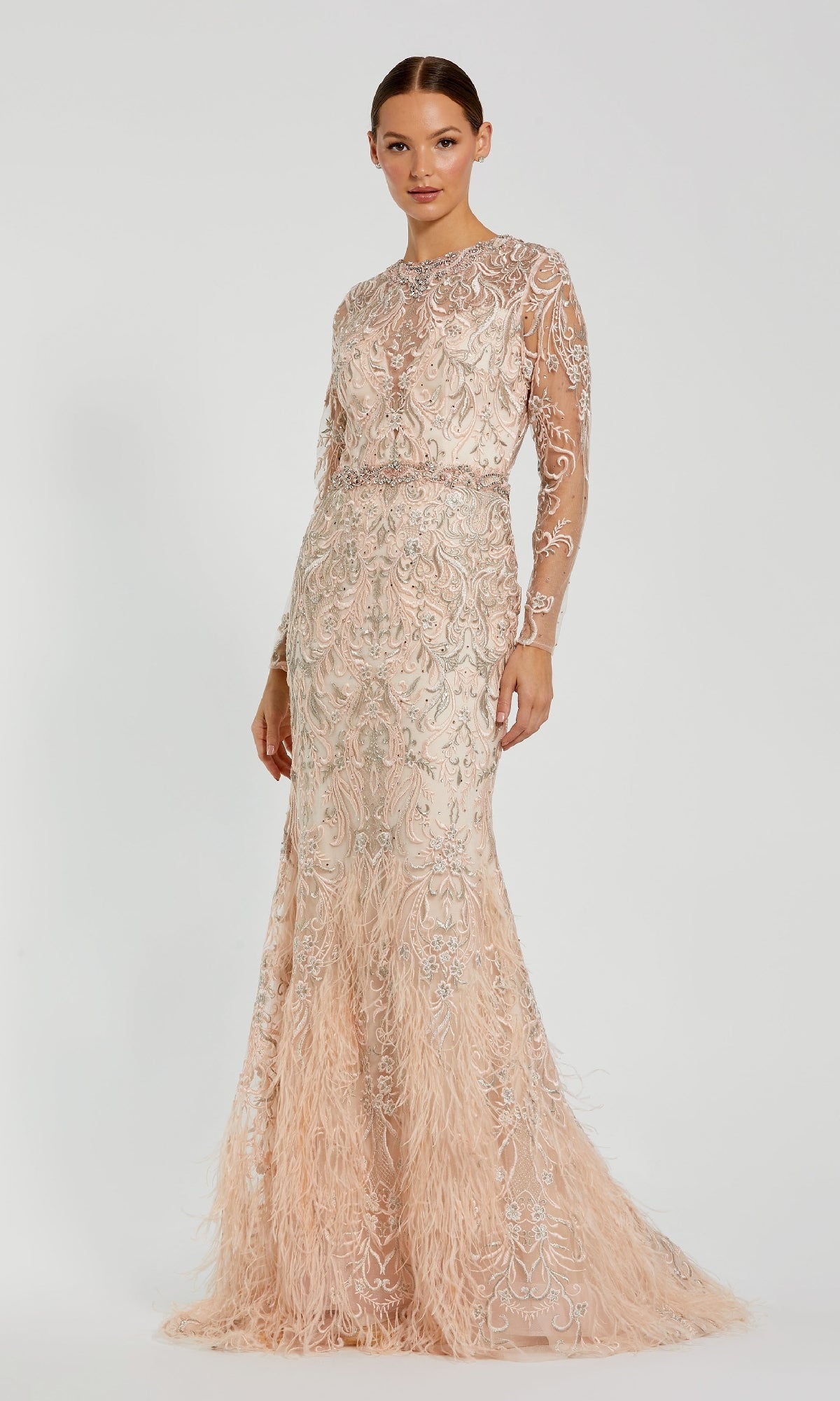 A woman poses against a white background wearing the Beaded Long Pink Formal Dress: Mac Duggal 79267, featuring intricate embroidery, sheer long sleeves, feather hem details, and a mermaid silhouette for an elegant look.